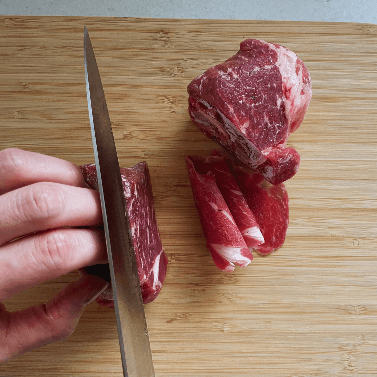 Slicing partially frozen beef thinly with a sharp knife