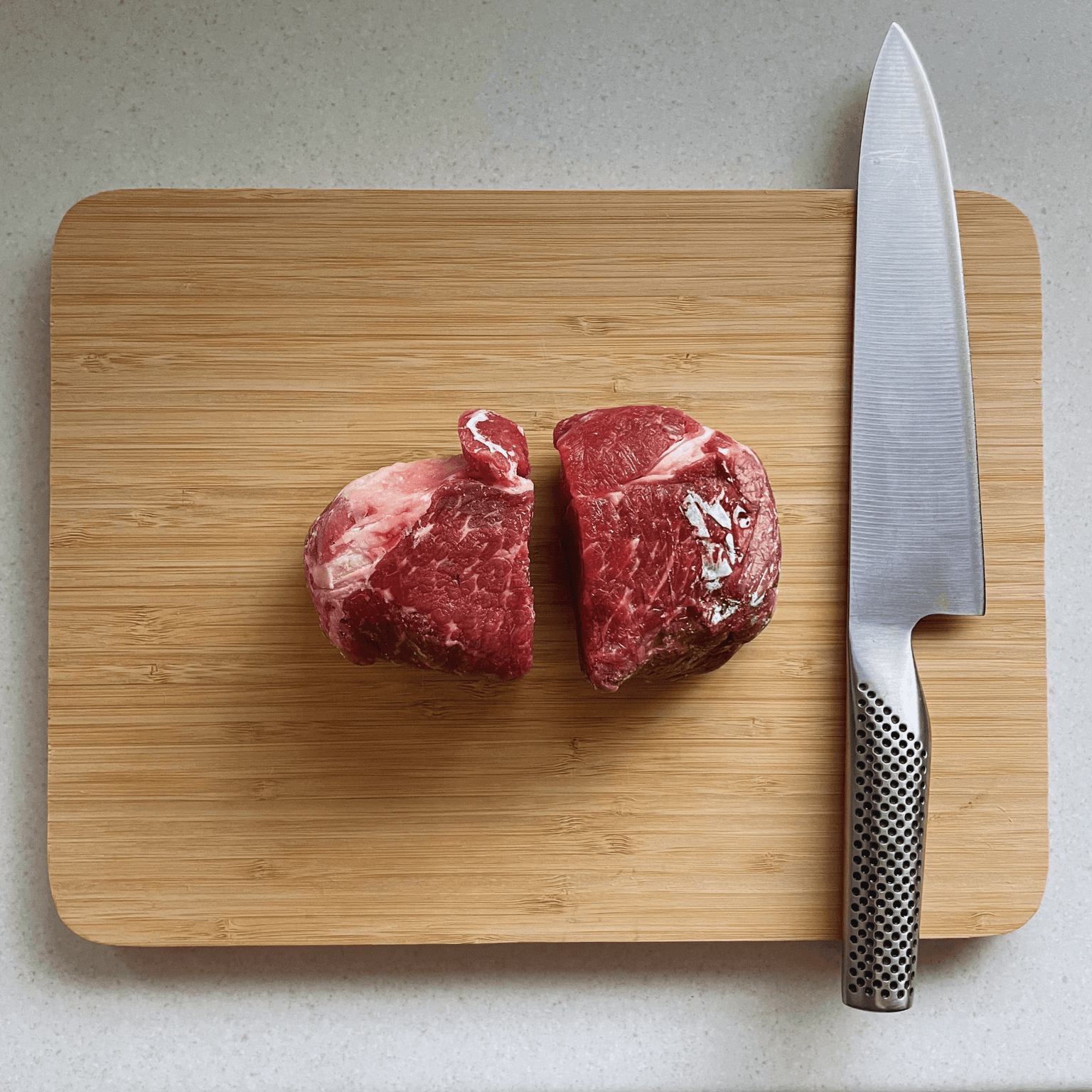 Two pieces of partially frozen beef ready to slice