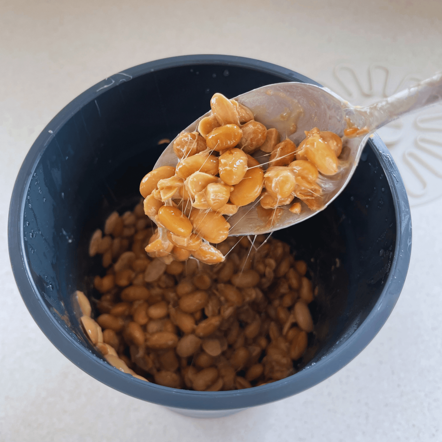 Homemade natto after fermenting with sticky strings on a spoon