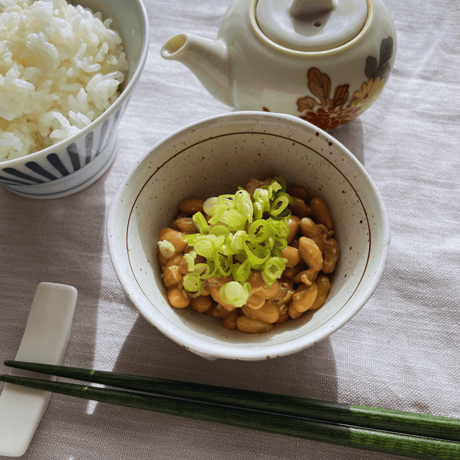 Homemade natto over rice with spring onion, rice and tea