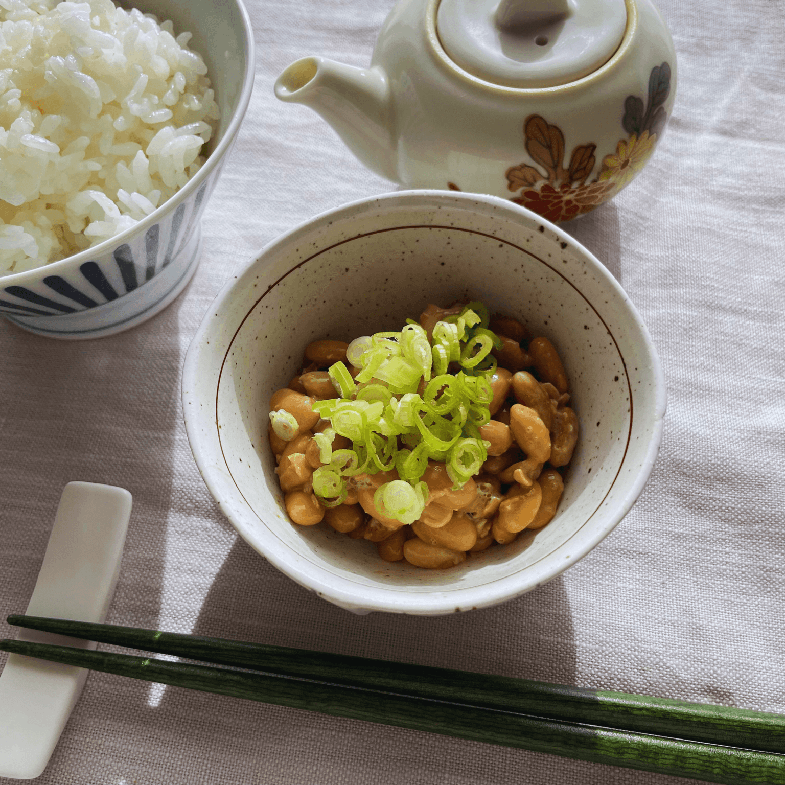 Homemade natto over rice with spring onion, rice and tea