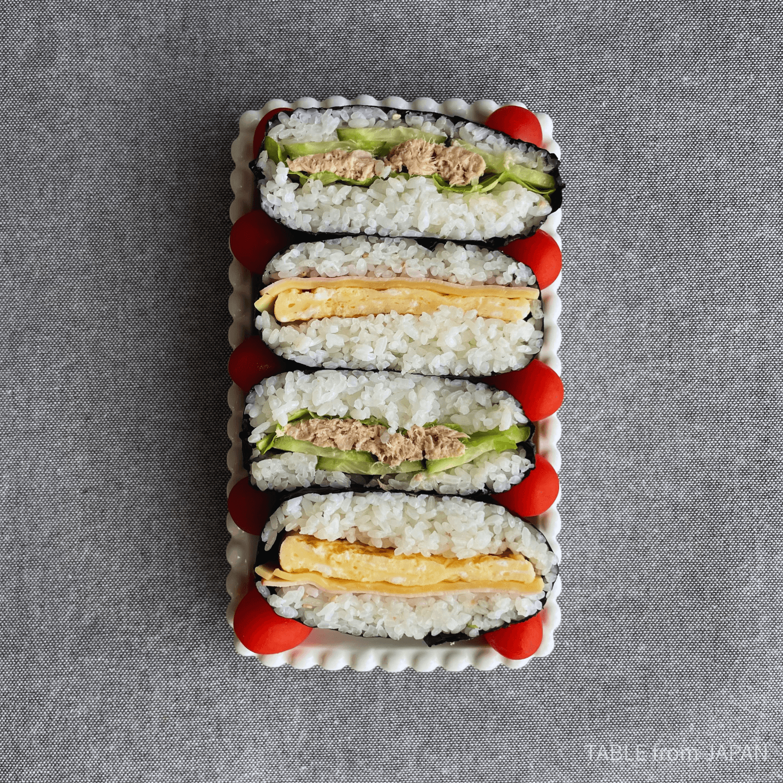 Square onigirazu wrapped in nori on a wooden board