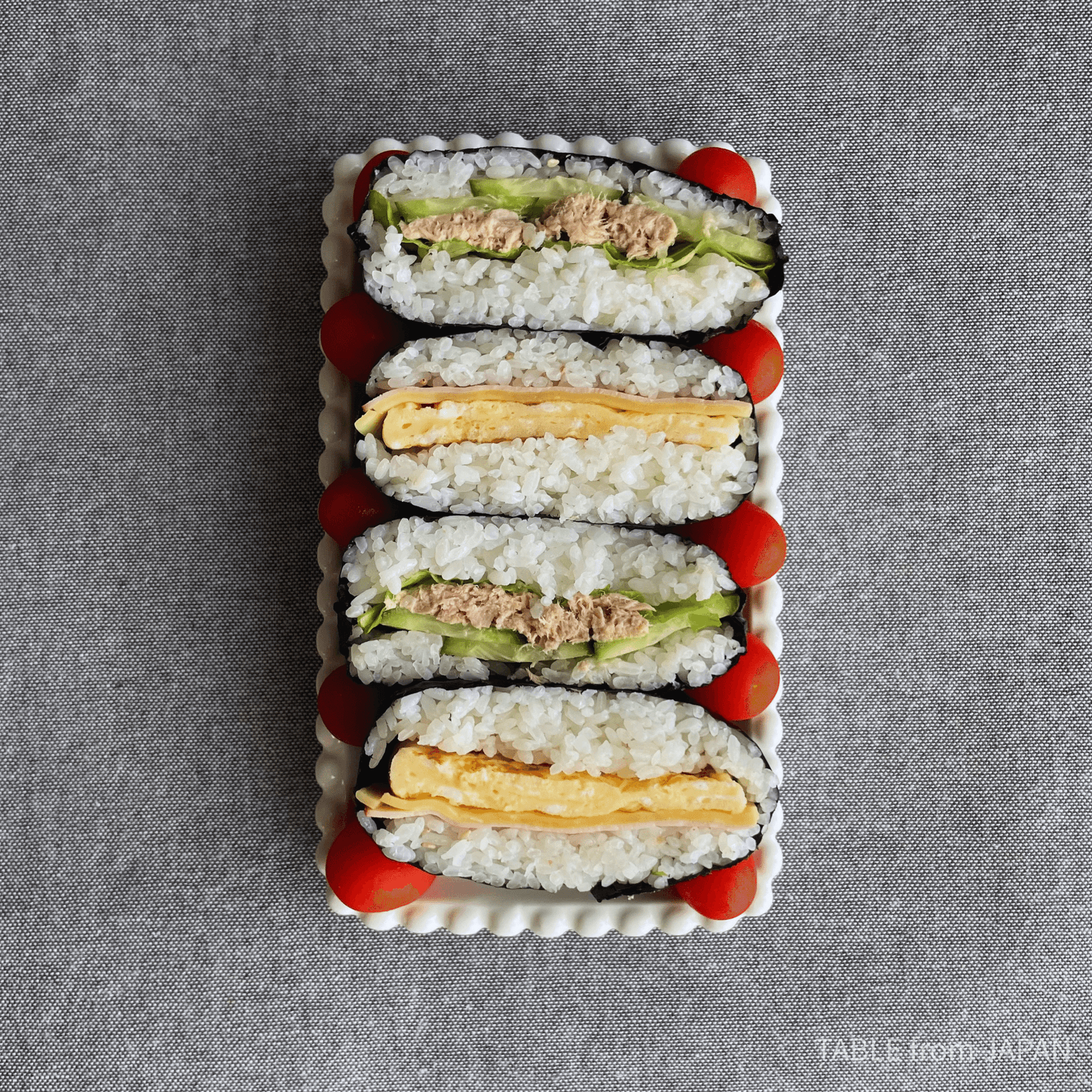 Square onigirazu wrapped in nori on a wooden board
